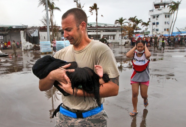 Binh sĩ Mỹ bế một em bé sơ sinh ra máy bay để sơ tán khỏi thành phố Tacloban, Philippines.