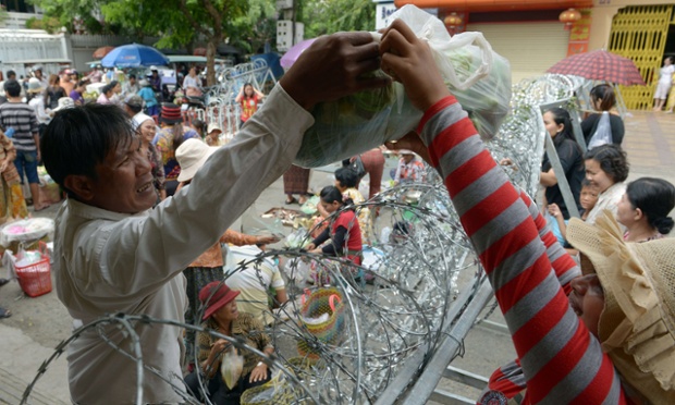Một phụ nữ đưa rau qua hàng rào dây thép gái cho một người đàn ông tại một khu chợ trong thời gian diễn ra cuộc họp Quốc hội ở thủ đô Phnom Penh, Campuchia.