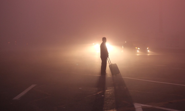 Một người đứng chờ taxi trên đường phố đầy sương mù trước nhà ga tàu hỏa ở thành phố Trường Xuân, Trung Quốc.