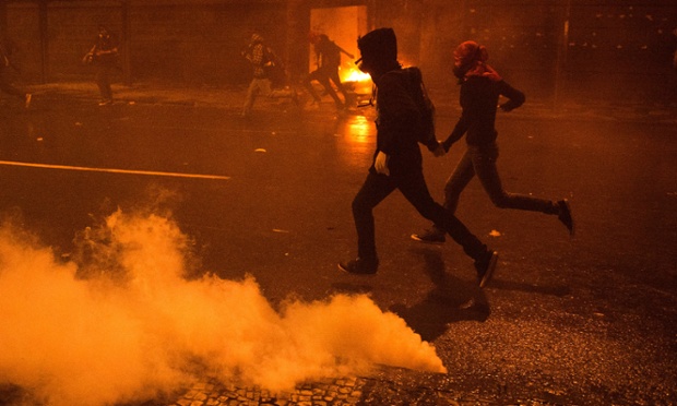 Những người biểu tình đeo mặt nạ bỏ chạy sau khi cảnh sát chống bạo động bắn đạn hơi cay tại Rio de Janeiro, Brazil.