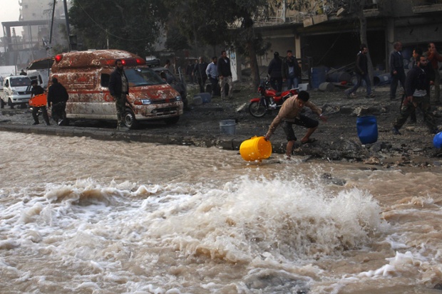 Nước phụt ra từ một ống dẫn nước trên đường bị vỡ sau khi không kích bởi quân đội chính phủ ở Aleppo, Syria.