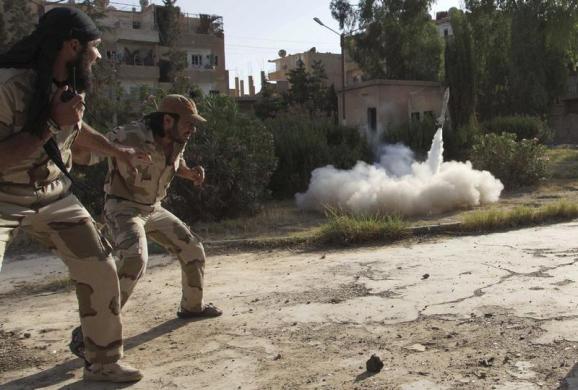 Các thành viên của quân đội tư do Syria lùi lại khi họ phóng rocket tự chế vào lực lượng quân đội trung thành với chính phủ ở Deir al-Zor, Syria.