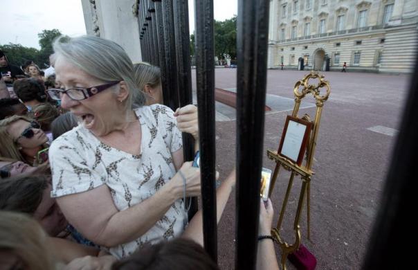 Mọi người  cố gắng nhìn bảng thông báo Công nương Kate hạ sinh Hoàng tử trước sân cung điện Hoàng gia ở London, Anh.