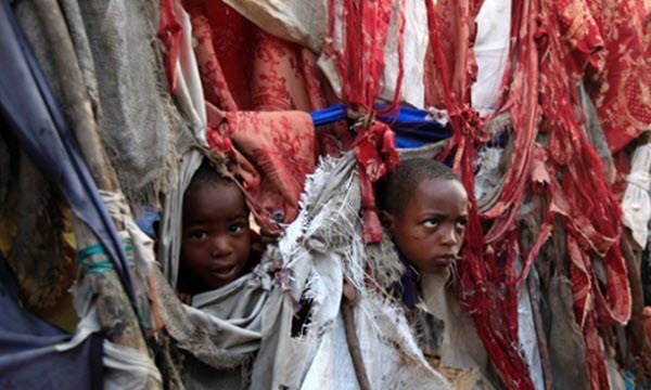 Trẻ em vô gia cư nhìn ra ngoài từ túp lều tạm rách nát ở Mogadishu, Somalia.