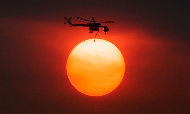 Khói che mờ Mặt trời, trong khi một máy bay trực thăng đang chở nước để dập tắt một đám cháy rừng ở Palm Springs, bang California, Mỹ.