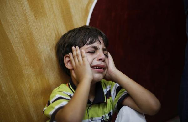 Một cậu bé Palestin ngồi khóc trong lễ tang của người bố ở Dải Gaza.