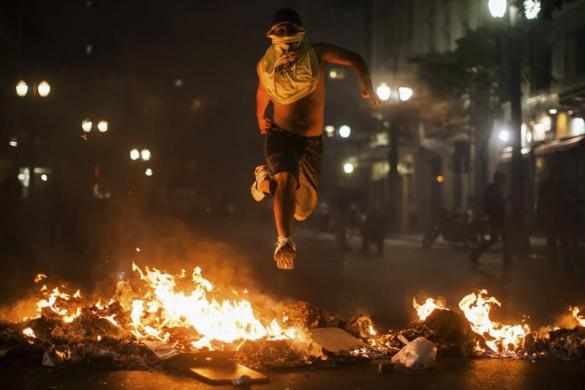 Một thanh niên nhảy qua đống lửa trong khi tham gia biểu tình phải đối nạn tham nhũng trong chính phủ ở thành phố Sao Paulo, Brazil
