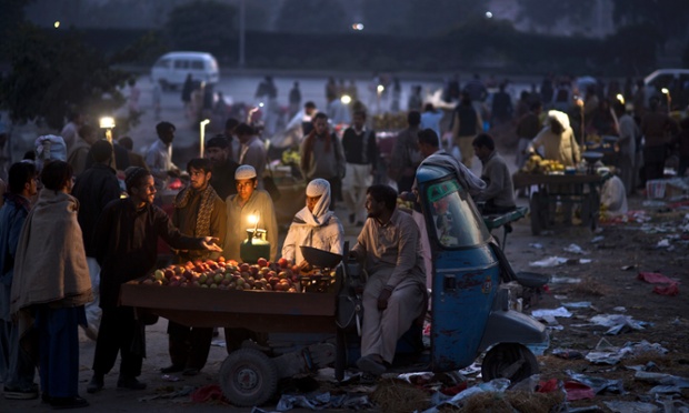 Một người bán táo trên xe ba bánh tại một khu chợ đêm ở Islamabad, Pakistan.