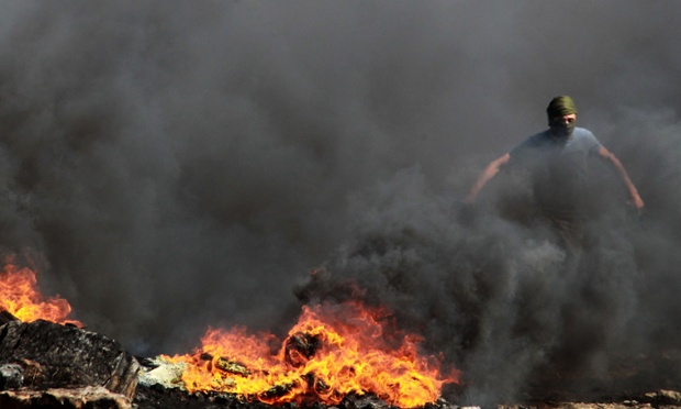 Một người biểu tình Palestin chạy qua đám cháy do đốt lốp xe ô tô trong cuộc đụ độ với binh sĩ Israel tại ngôi làng Kfar Qaddum, Bờ Tây.