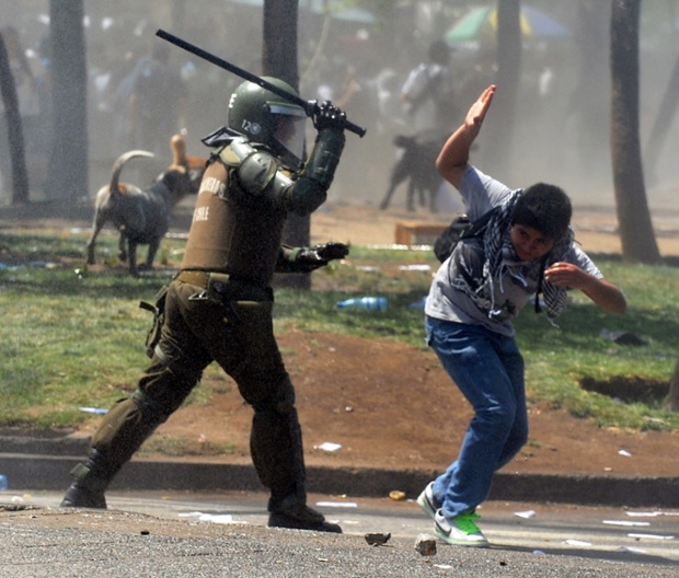 Cảnh sát chống bạo động dùng gậy đánh một sinh viên biểu tình chống chính phủ ở Santiago, Chile.