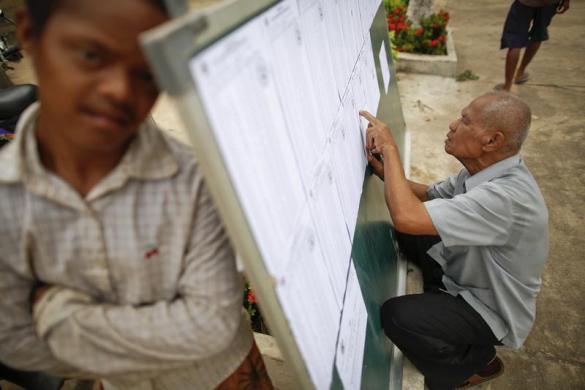 Một người đàn ông kiểm tra danh sách cử tri trên bảng bầu cử ở ngoại ô thủ đô Phnom Penh, Cam-pu-chia.