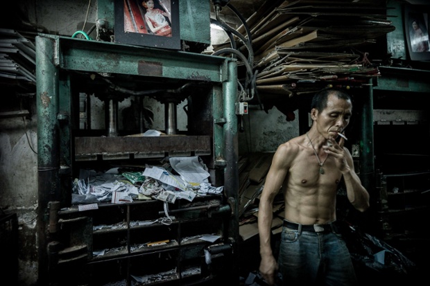 Một công nhân hút lá tại nhà máy tái chế giấy vụn ở Hong Kong.