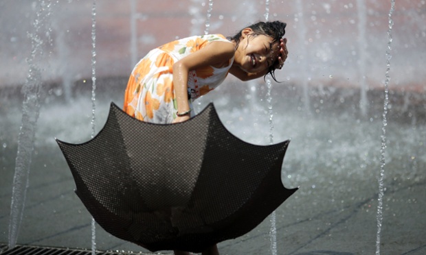 Bé gái cầm ô chơi trong đài phun nước ở Thượng Hải, Trung Quốc, khi nhiệt độ ngoài trời lên tới 40 độ C.