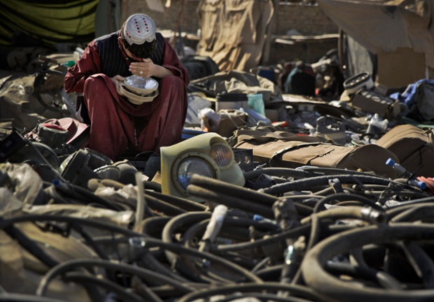 Một người buôn bán đồ phế liệu đang kiểm tra chiếc đèn pha ô tô mua tại một bãi rác thải của quân đội Mỹ ở Kandahar, Afghanistan.