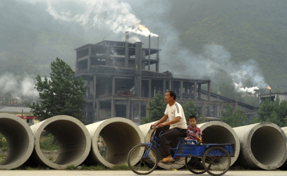 Hai cha con người Trung Quốc chở nhau qua một nhà máy ô nhiễm ở huyện Baokang, tỉnh Hồ Bắc