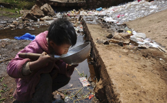 Một cậu bé uống nước gần dòng suối ở huyện Fuyuan, Vân Nam, Trung Quốc