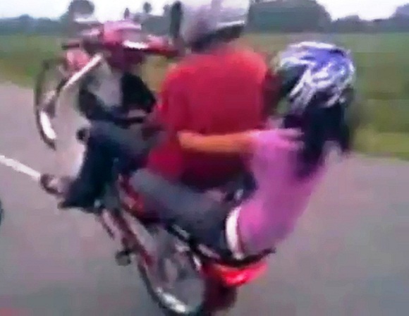 Đôi trai gái bốc đầu xe máy và biểu diễn các tư thế mạo hiểm trên xe (Ảnh cắt từ clip)