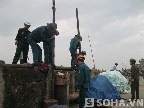 Lực lượng công an xã và dân quân tự vệ hỗ trợ người dân giằng chống nhà cửa và di dời tránh bão.