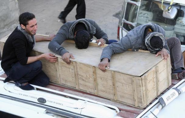 
	Ba người đàn ông khóc và ôm quan tài của một người thân thiệt mạng trong một vụ tấn công tại thị trấn Yusfiya, Iraq.