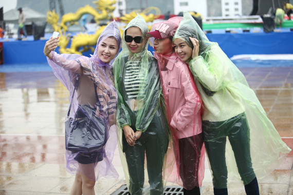 	Thời tiết mưa gió khiến các người đẹp phải mặc áo mưa và luyện tập.