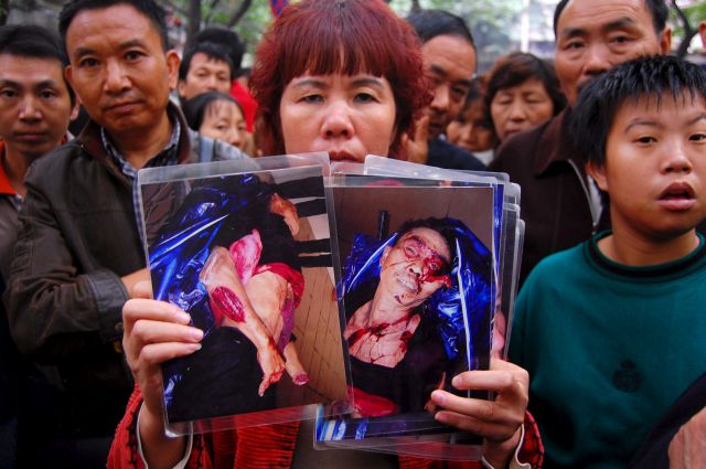 
	Một người dân Trùng Khánh giơ những tấm ảnh người thân của cô bị băng đảng đánh đập.