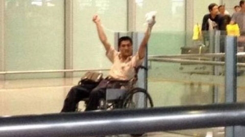 
	Ji Zhongxing giơ cao túi thuốc nổ màu trắng tại sân bay quốc tế Bắc Kinh.