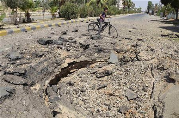 	Một đứa trẻ đi xe đạp gần đoạn đường bị bom phá nát ở ngoại ô Damacus.