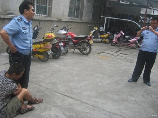 	Một người bán hàng rong ôm chân nhân viên trật tự đô thị ở huyện Thành Cố (Thiểm Tây, TQ) để xin lại chiếc cân bị thu giữ. Nhân viên này thản nhiên đứng tạo dáng cho đồng nghiệp chụp ảnh