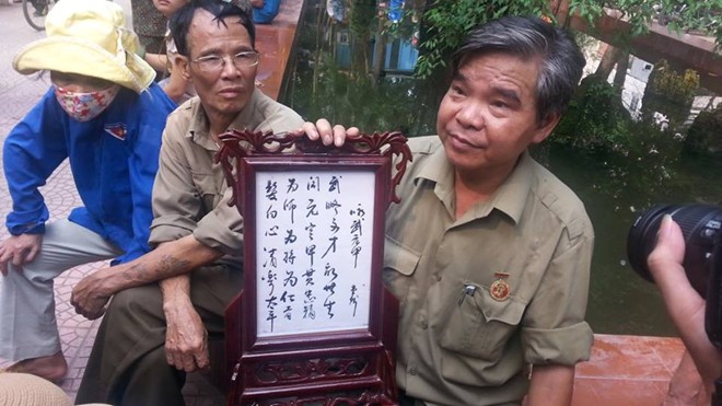 Ông Đinh Hữu Phương, sinh năm 1946, mang theo bức thư họa tri ân Đại tướng, vào vườn hoa để theo dõi Lễ viếng. Ảnh: Trí Thức