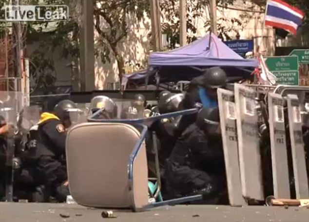 The riot police can be seen sheltering behind a wall of shields as missiles are hurled from the crowd in the latest round of Thailands protests