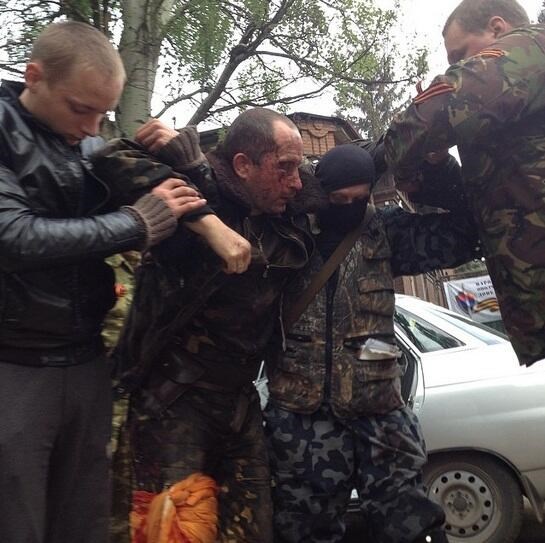 Phi công Ukraine trên chiếc trực thăng bị bắn hạ được lực lượng tự vệ địa phương đưa khỏi hiện trường (Nguồn: RT)