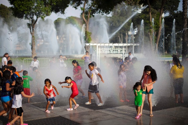 Trẻ em thích thú chơi trong đài phun nước ở công viên Khám phá, Lima, Peru.