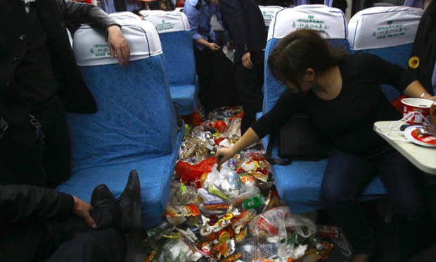 Hành khách vứt rác xuống sàn khi công nhân vê sinh thu dọn tới trên một chuyến tàu Tết từ Thâm Quyến tới Thặng Châu, Trung Quốc.