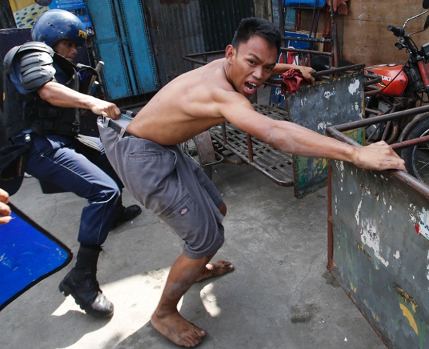 Cảnh sát túm quần một người dân chống đối lệnh giải tỏa ở Manila, Philippines.