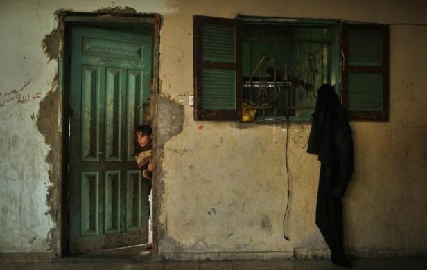 Một bé gái người Palestine nhìn ra ngoài từ trong ngôi nhà của gia đình cô bé ở Dải Gaza.