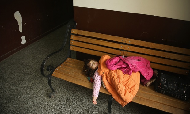 Bé gái ngủ trên ghế cạnh lối đi trong một trung tâm tị nạn ở Sofia, Bulgaria.