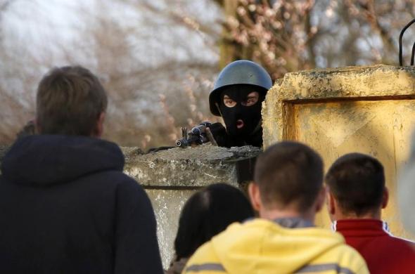 Một binh sĩ Ukraine chĩa súng vào những người biểu tình ủng hộ Nga tập trung trước căn cứ quân sự ở Kramatorsk.