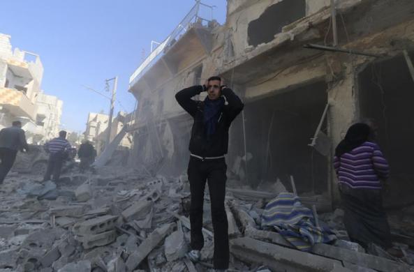 Một người đàn ông ôm đầu đứng trên hiện trường vụ không kích bởi quân đội chính phủ ở Aleppo, Syria.