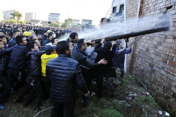 Mọi người cố gắng phá tường để lính cứu hỏa chữa cháy trong một nhà máy ở Ôn Lĩnh, tỉnh Chiết Giang, Trung Quốc.