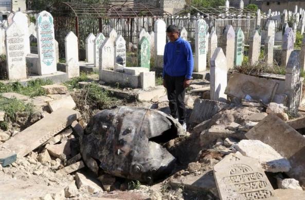 Người đàn ông nhìn quả bom chưa nổ được thả bởi lực lượng trung thành với Tổng thống Syria Bashar al-Assad tại một nghĩa trang ở Aleppo.