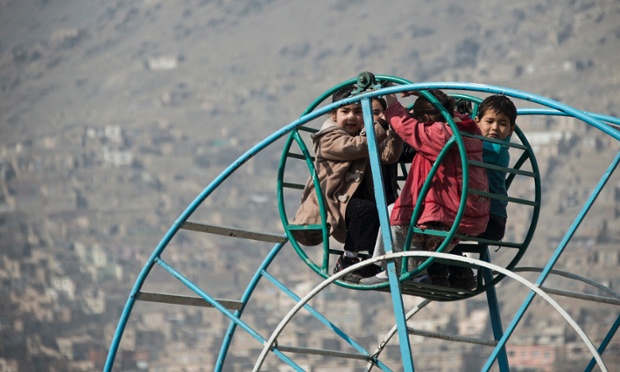 Trẻ em chơi trên vòng đu quay gần một nghĩa trang ở Kabul, Afghanistan.