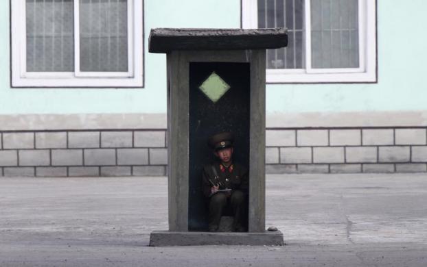 Một binh sĩ Triều Tiên ngồi trong trạm gác trên bờ sông Yalu gần thị trấn Sinuiju đối diện với thành phố Đan Đông, Trung Quốc.