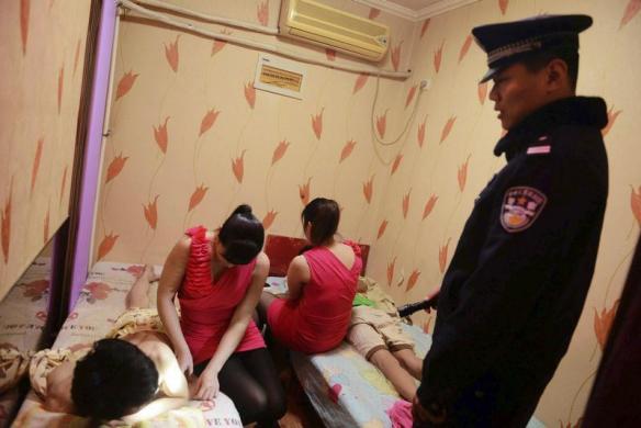 Cảnh sát nói chuyện với một người đàn ông trong cuộc kiểm tra chống tội phạm mại dâm ở Thanh Đảo, tỉnh Sơn Đông, Trung Quốc.