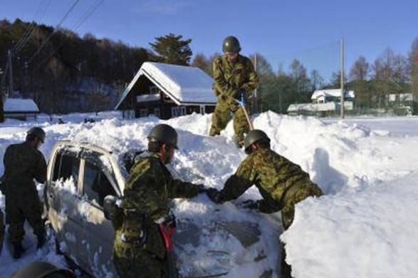 Các binh sĩ Nhật Bản dọn tuyết bao phủ một chiếc ô tô trên đường ở tỉnh Yamanashi, gần thủ đô Tokyo.