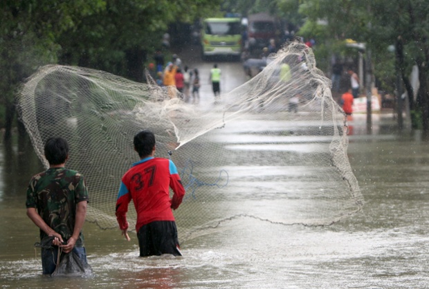 Người dân quăng chài đánh cá trên đường phố ngập lụt ở Jakarta, Indonesia.