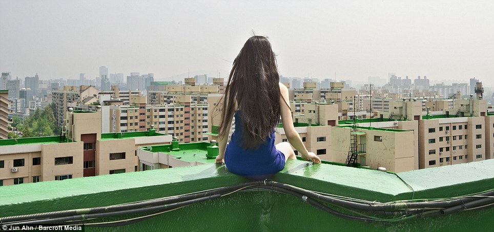 Tháng Sáu Ahn ngồi trên các cạnh của mái nhà nhìn ra Seoul, Hàn Quốc