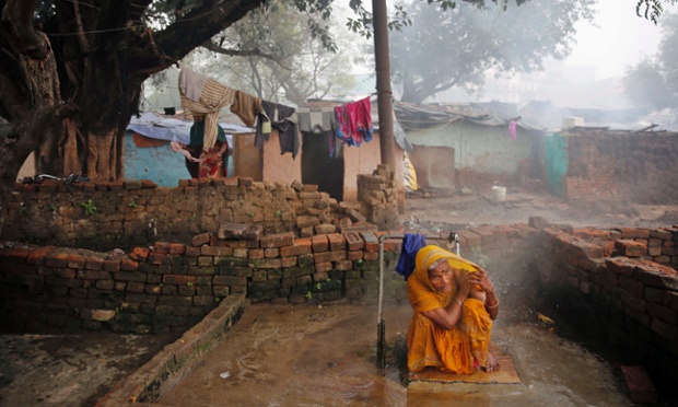 Một phụ nữ tắm dưới vòi nước lạnh trong buổi sáng mùa đông tại khu ổ chuột ở Allahabad, Ấn Độ.