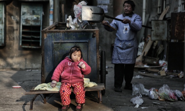 Bé gái ngồi trên xe kéo rác trong khi bà đang làm việc ở Nam Xương, tỉnh Giang Tây, Trung Quốc.