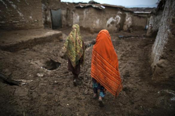 Hai bé gái đi trên con đường bùn lầy trở về nhà của chúng tại một khu ổ chuột ở ngoại ô Islamabad, Pakistan.