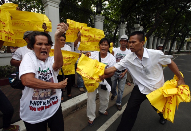 Nhân viên an ninh thu khẩu khẩu hiệu của các nông dân tham gia biểu tình bên ngoài Cung điện Malacanang ở Manila, Philippines.